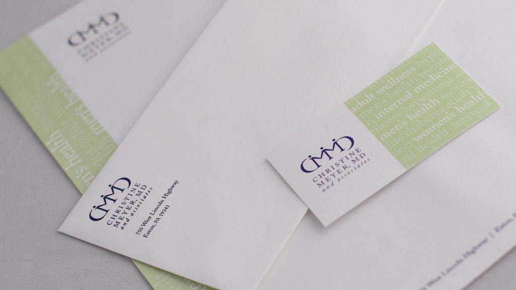 Detailed photo of the stationery for Christine Meyer, MD. Includes the CMMD logo and identity developed for her practice which combines her initials and professional designation in a palendromic mark with people holding hands to represent care.